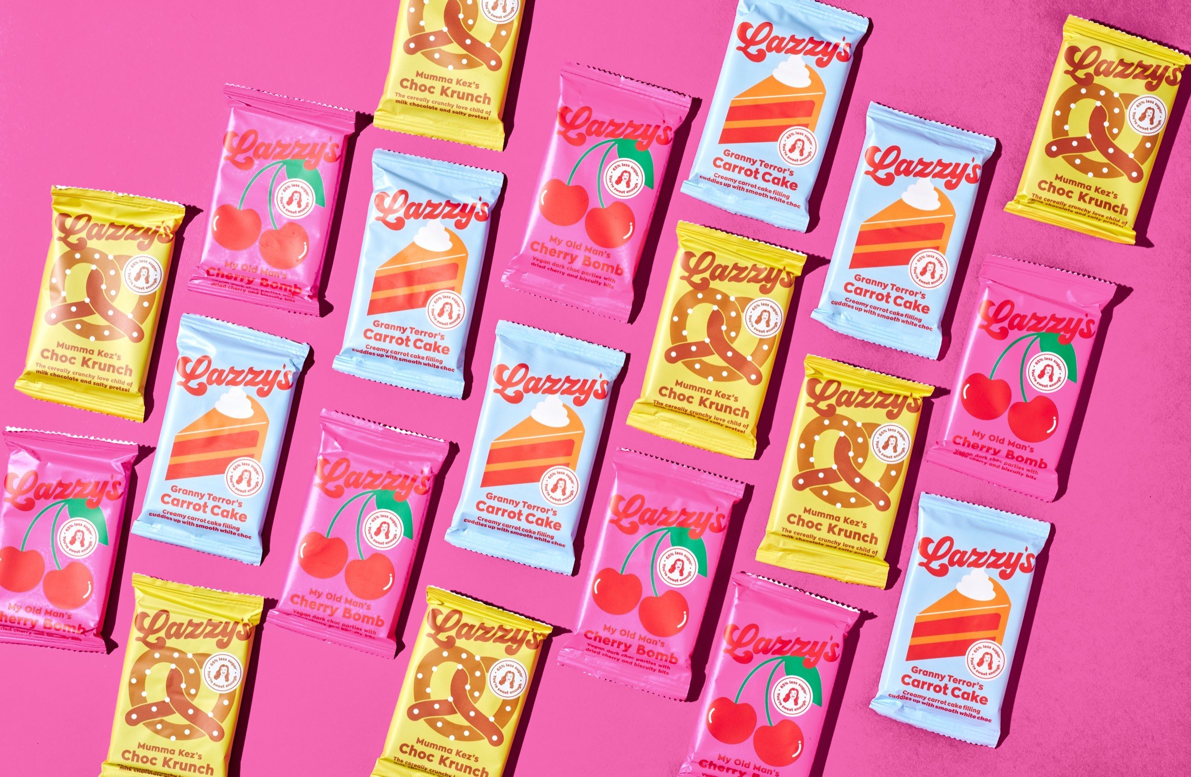 Rows of Lazzy's Cherry Bomb, Choc Krunch and Carrot Cake bars on a pink background